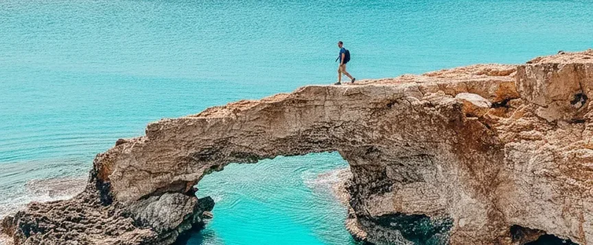 Hiker exploring a natural rock arch along the UAE coastline