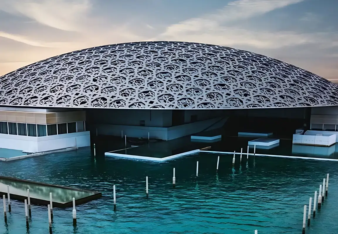 Geometric dome of Louvre Abu Dhabi reflected over the surrounding water